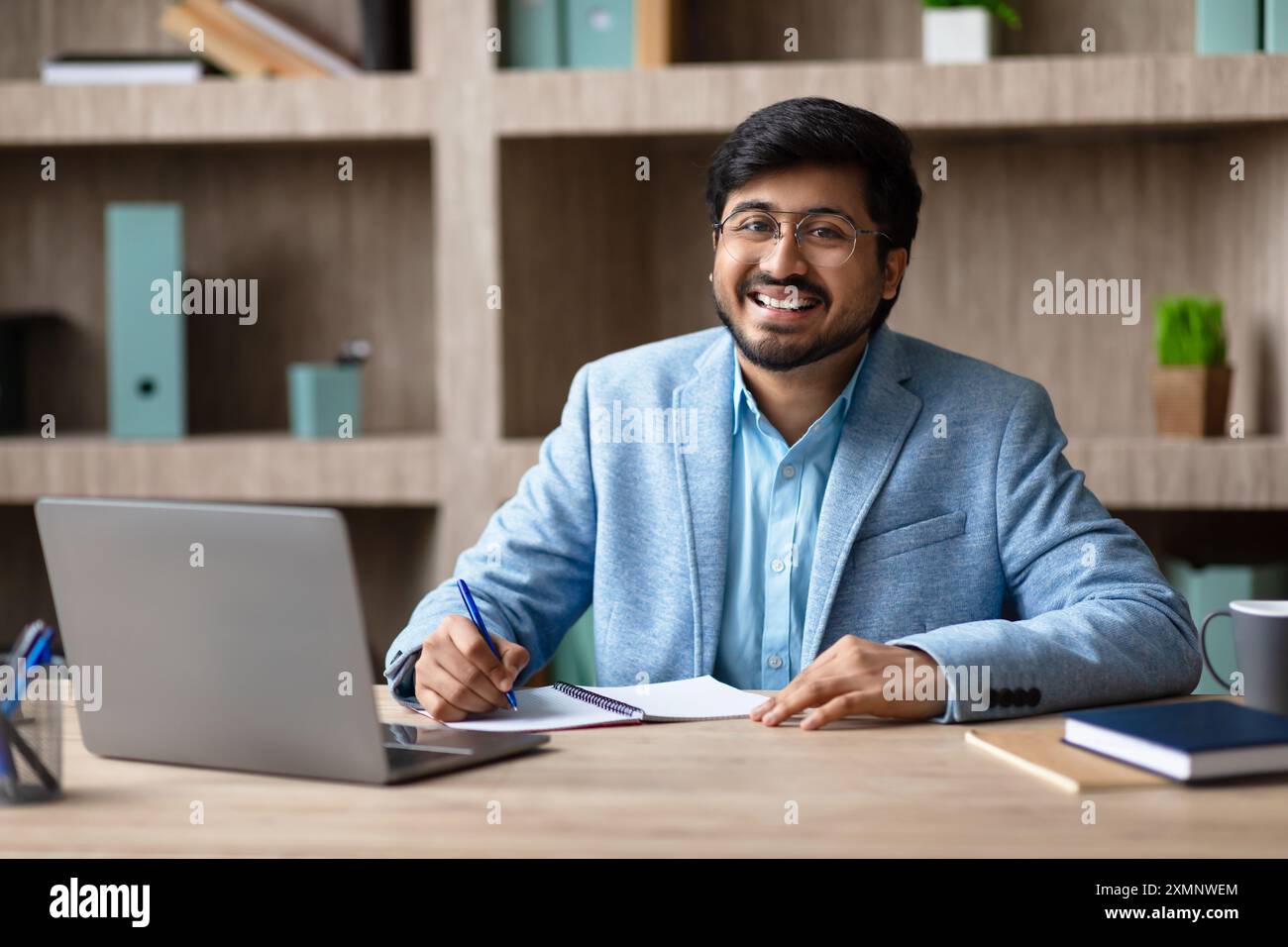 smiling-businessman-working-at-desk-in-modern-office-2XMNWEM.jpg